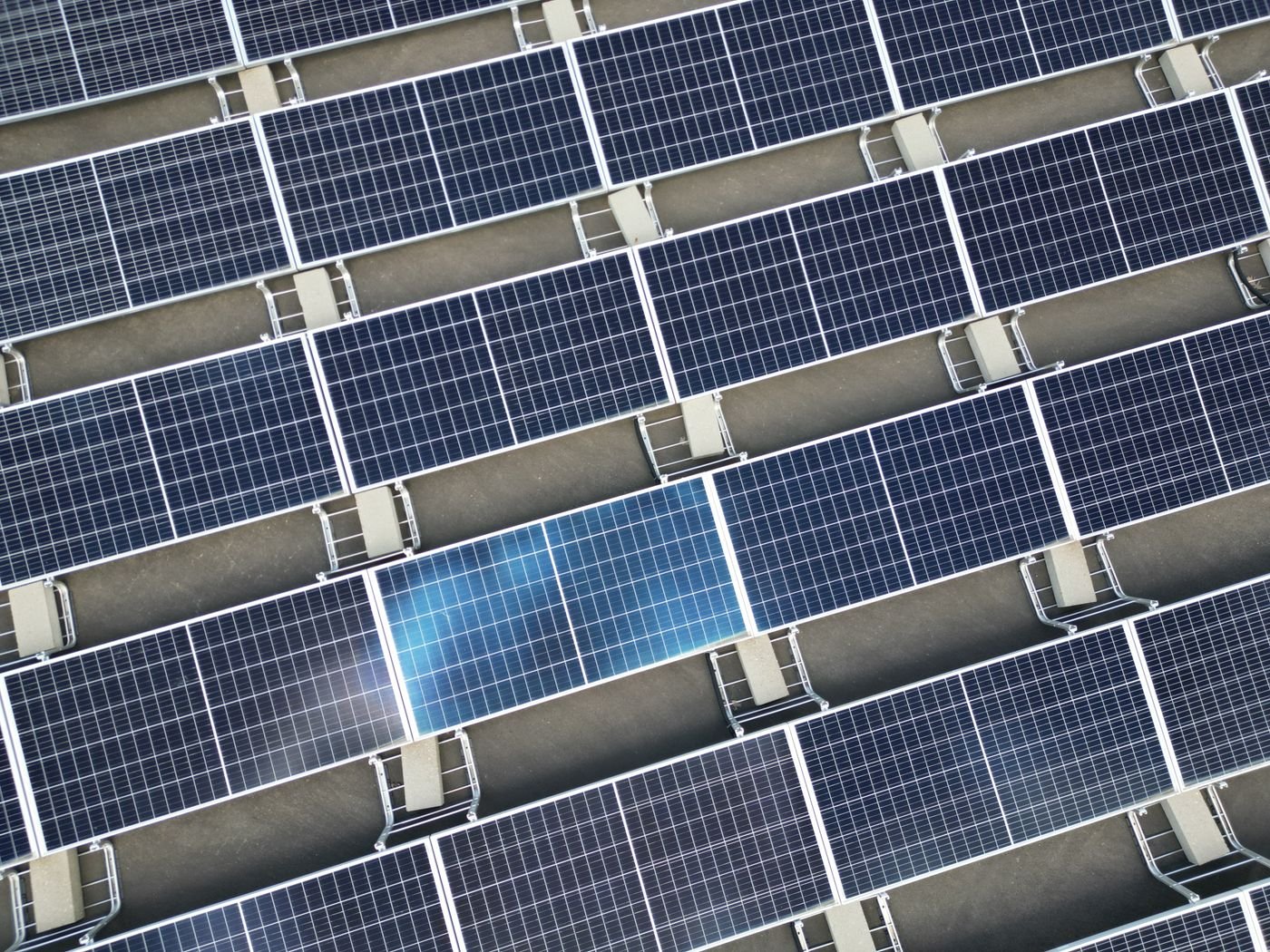 A solar module being lifted into position near a wall or balcony