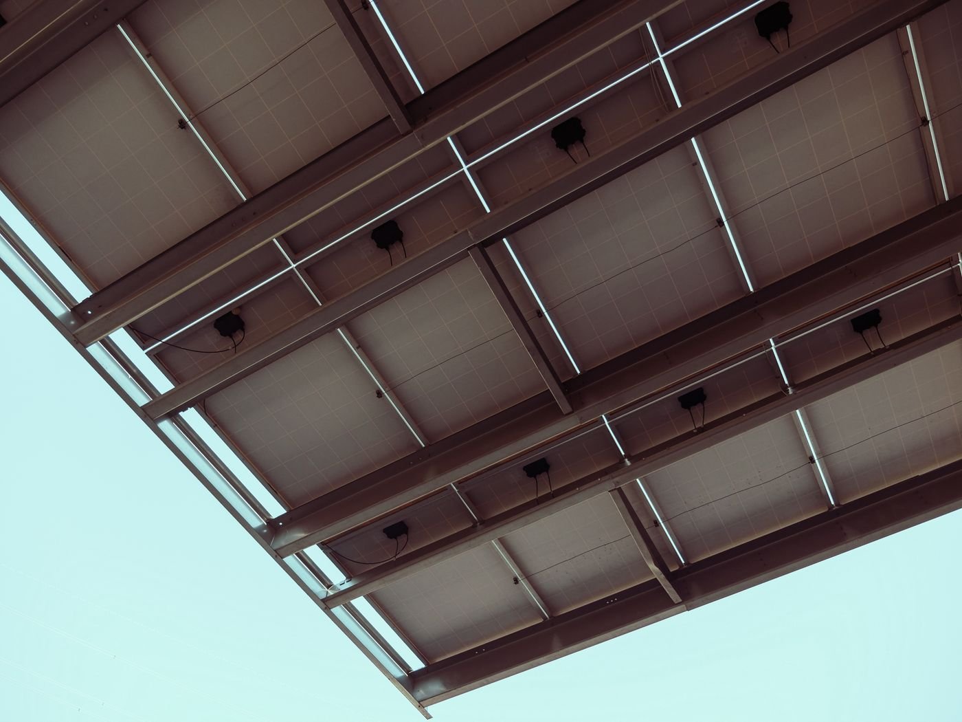 Close-up of a bifacial solar panel mounting structure with rails and clamps under the modules