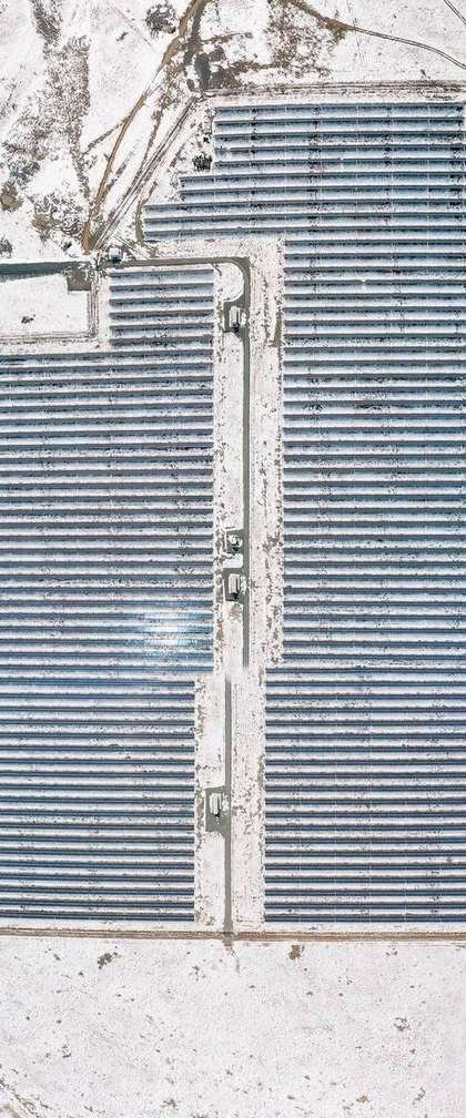 Aerial view of fixed tilt rows in snow, showing the wide row spacing a solar tracker vs fixed tilt comparison depends on